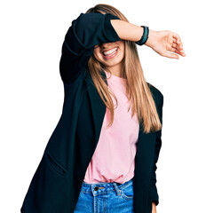 Wall Mural - Hispanic young woman wearing business jacket and glasses covering eyes with arm smiling cheerful and funny. blind concept.