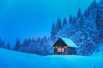 Wall Mural - A lonely wooden house surrounded by snowy pine trees in a mountain glade deep within the woods in a wintery landscape. Christmas holiday postcard. Snowy mountains forest