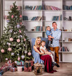 A young family with children welcomes the New Year near the Christmas tree