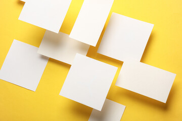 Composition of floating white square memo paper and business cards on yellow background. Mockup. Business concept