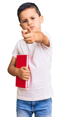 Wall Mural - Little cute boy kid reading a book pointing with finger to the camera and to you, confident gesture looking serious