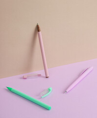 Wall Mural - Modern and creative composition with multicolored pens on a two tone pastel background. Minimal still life. Business, education concept