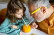 © ADDICTIVE STOCK - Senior man and girl drinking fruit juice on table