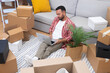 © olga_demina - Young brunette guy sits with laptop among boxes in new flat checking availability of decorations for placing in interior of apartment in electronic catalog on laptop