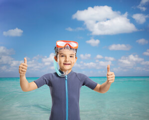 Wall Mural - Little boy with a snorkeling mask showing thumbs up by the sea