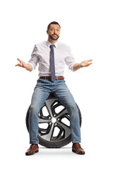 Poster - Serious young man sitting on a car tire