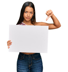 Sticker - Beautiful hispanic woman holding blank empty banner with angry face, negative sign showing dislike with thumbs down, rejection concept