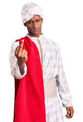 Canvas Print - African handsome man wearing tradition sherwani saree clothes showing middle finger, impolite and rude fuck off expression