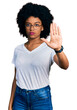 Young african american woman wearing casual white t shirt doing stop sing with palm of the hand. warning expression with negative and serious gesture on the face.