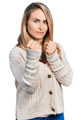 Wall Mural - Young blonde woman wearing casual clothes ready to fight with fist defense gesture, angry and upset face, afraid of problem