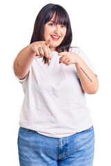 Poster - Young plus size woman wearing casual clothes pointing to you and the camera with fingers, smiling positive and cheerful