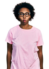 Sticker - African american woman with afro hair wearing casual clothes and glasses making fish face with lips, crazy and comical gesture. funny expression.