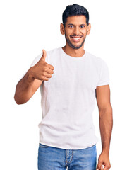 Sticker - Young latin man wearing casual clothes doing happy thumbs up gesture with hand. approving expression looking at the camera showing success.