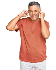 Canvas Print - Handsome middle age man wearing casual clothes covering ears with fingers with annoyed expression for the noise of loud music. deaf concept.