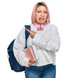 © Krakenimages.com - Hispanic woman with pink hair wearing student backpack and headphones pointing aside worried and nervous with forefinger, concerned and surprised expression