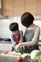 Wall Mural - 一緒にキッチンで楽しく料理をする親子 子供のお手伝いの縦の写真 左にコピースペースあり