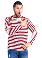 Sticker - Young handsome man wearing striped sweater surprised pointing with finger to the side, open mouth amazed expression.