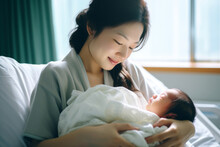 Beautiful Young Mother Holding Her Newborn In Maternity Ward After Delivery. New Mom Welcoming Her First Child Into The World. Woman After Labor In Hospital Bed.
