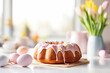 Beautifully decorated Easter bundt cake with white frosting and pastel colored sugar eggs. Glazed donut cake for Easter celebration with family at home. Traditional Easter dishes.