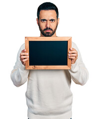 Sticker - Young hispanic man with beard holding blackboard skeptic and nervous, frowning upset because of problem. negative person.