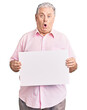 © Krakenimages.com - Senior grey-haired man holding blank empty banner scared and amazed with open mouth for surprise, disbelief face