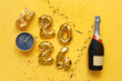 Figure 2024 made of balloons with Christmas decorations, alarm clock and champagne bottle on orange background