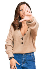 Sticker - Young brunette woman wearing casual winter sweater doing stop sing with palm of the hand. warning expression with negative and serious gesture on the face.