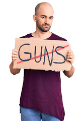 Poster - Young handsome man holding prohibited guns banner thinking attitude and sober expression looking self confident