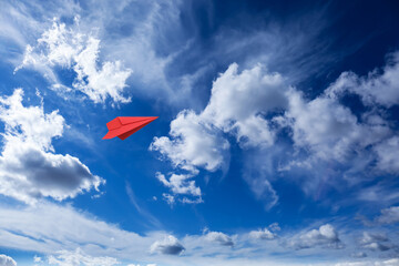 Poster - Red paper plane flying in blue sky with clouds