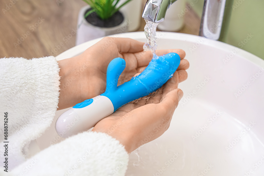 Woman washing vibrator over sink, closeup