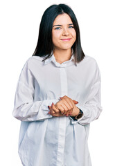 Poster - Young brunette woman with blue eyes wearing oversize white shirt with hands together and crossed fingers smiling relaxed and cheerful. success and optimistic