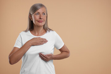 Sticker - Beautiful senior woman doing breast self-examination on light brown background. Space for text