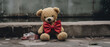 Abandoned and unloved stuffed bear toy with a red bowtie sitting lost and lonely on an empty urban street.
