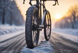 Close up bike tire in the snowy road blurred winter sunrise background