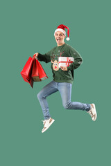 Sticker - Handsome young happy man with gift boxes and shopping bags jumping on green background