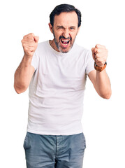 Sticker - Middle age handsome man wearing casual t-shirt angry and mad raising fists frustrated and furious while shouting with anger. rage and aggressive concept.