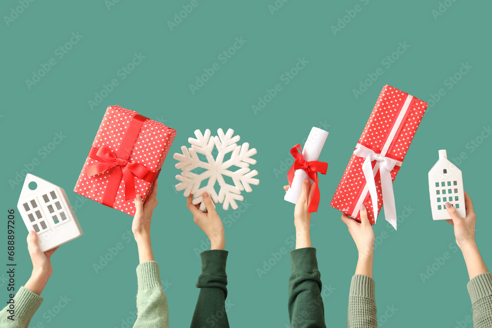 Hands holding gift boxes and Christmas decor on green background