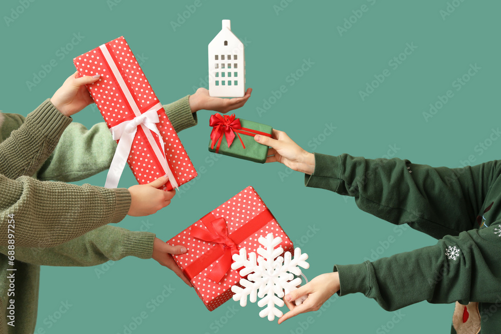 Hands holding gift boxes and Christmas decor on green background