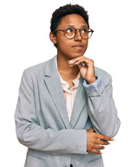 Wall Mural - Young african american woman wearing business clothes with hand on chin thinking about question, pensive expression. smiling and thoughtful face. doubt concept.