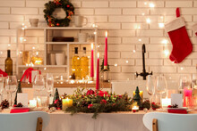 Festive table setting with Christmas decorations and glowing lights in kitchen at evening