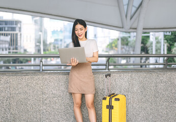 Wall Mural - Business travel asian woman using laptop computer standing at outdoor on day