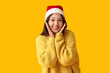 © Pixel-Shot - Happy young Asian woman in Santa hat on yellow background