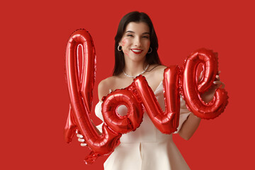 Sticker - Happy young woman with kiss marks on her face and air balloons in shape of word LOVE on red background