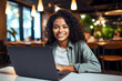 © idcreative.ddid - An African American young and curly hair woman using laptop sitting at desk and smiling to the camera. Working or learning online class concept.