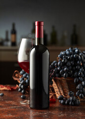 Bottle and glass of red wine with grapes on a vintage table.