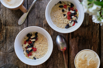 Sticker - Oatmeal with raisins, dried cherries and almond petals. wooden background, side view