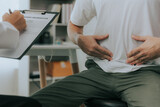 Fototapeta  - Crohn's disease or ulcerative colitis concept. Doctor counseling male patient with abdominal pain in hospital examination room