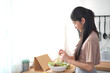 © DG PhotoStock - Happy beautiful Asian young woman making a vegetable salad in kitchen.