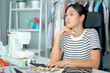 © DG PhotoStock - Happy beautiful Asian young woman working in the fashion design studio.