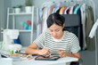 © DG PhotoStock - Happy beautiful Asian young woman working in the fashion design studio.